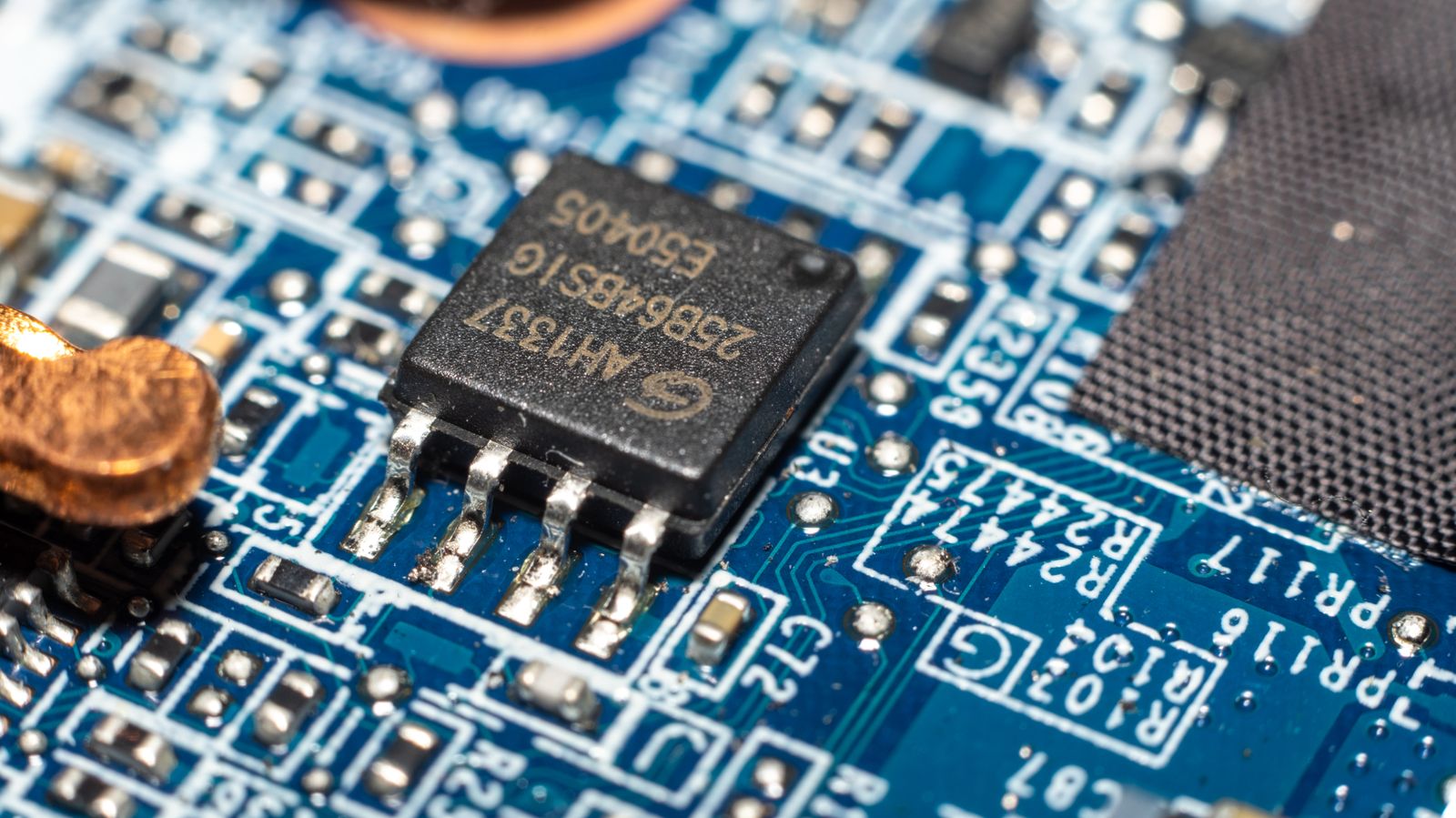 Detailed macro image of a microchip mounted on a blue circuit board.