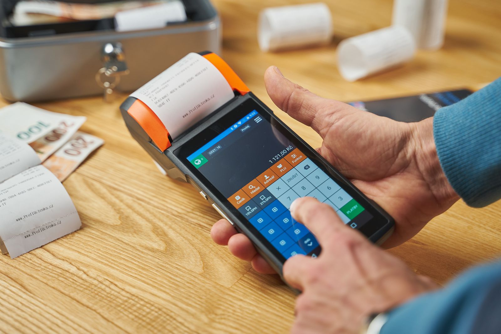 Close-up of hands operating a modern point of sale device with a printed receipt.